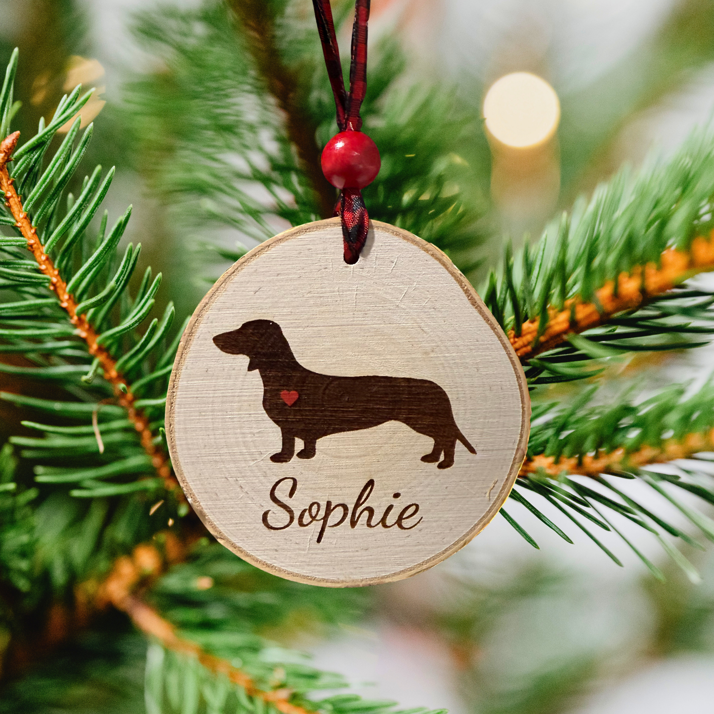 Wooden ornament with dachshund silhouette and 'Sophie' on a Christmas tree.