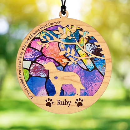 Decorative pet memorial pendant with colorful design and engraved text, against a blurred natural background.
